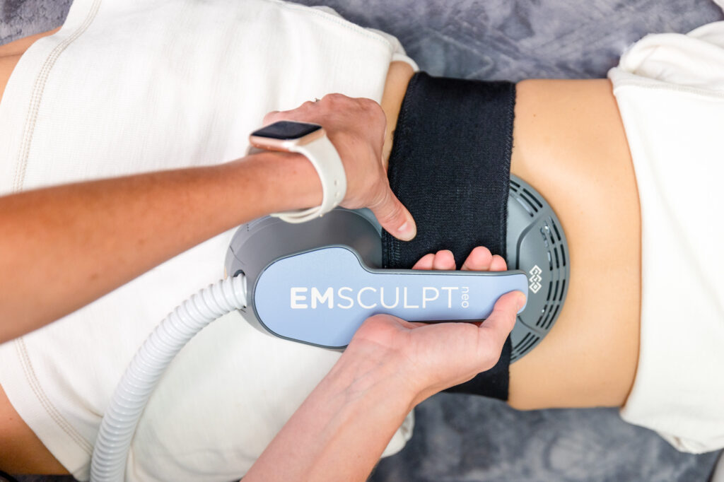 A specialist applies an Emsculpt NEO applicator to a patient's abdomen to begin her body sculpting in McKinney.