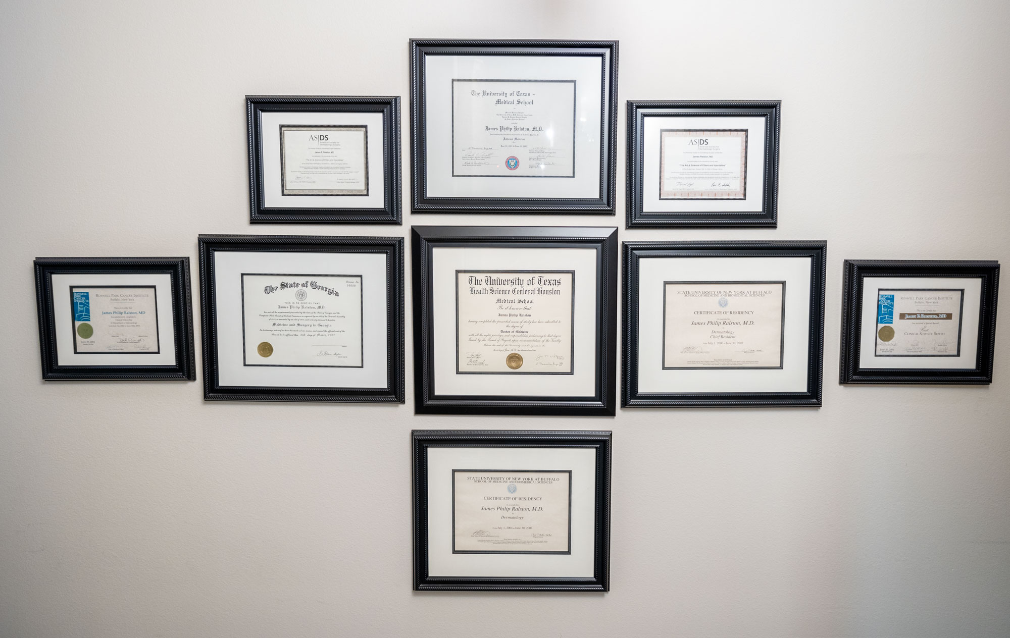 A wall at the Dermatology Center of McKinney, with framed certificates for Dr. James Ralston, a dermatologist near Prosper, TX.