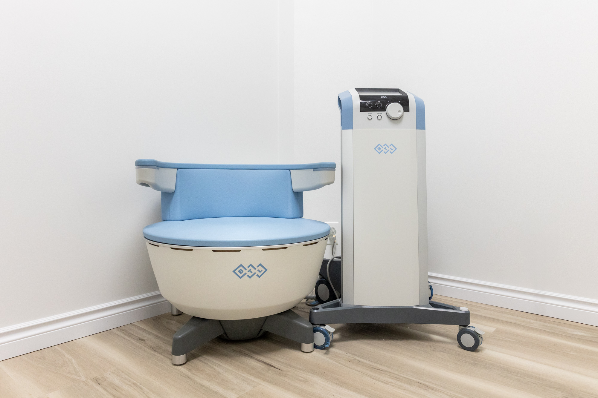 The Emsella chair sits next to the workstation in a medical aesthetics facility. The chair is used for pelvic floor therapy in McKinney.